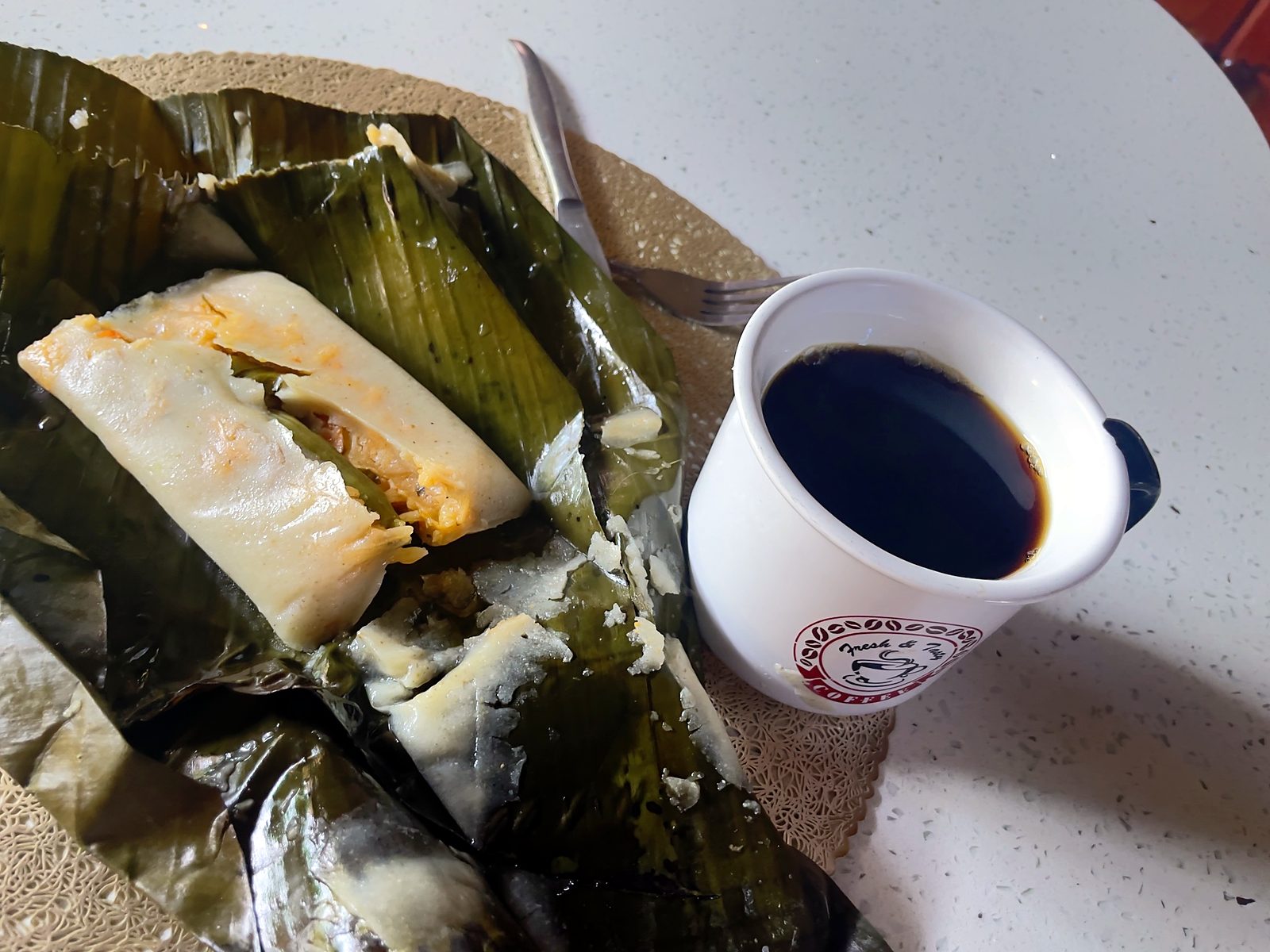 A Costa Rican tamal in banana leaves with a cup of black coffee