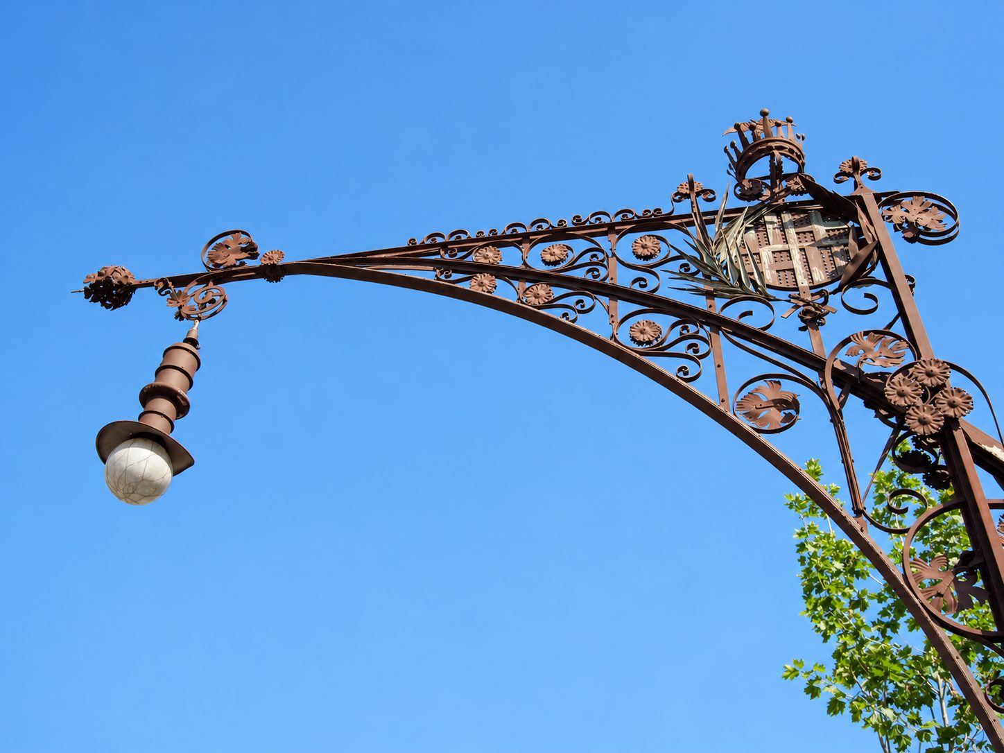 An iron street lamp against a blue sky in Barcelona