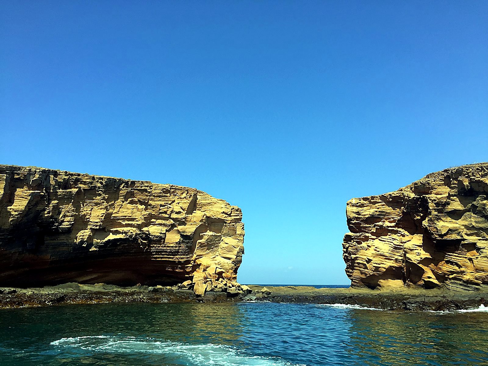 Two rock cliffs with clear water between them in the Galápagos