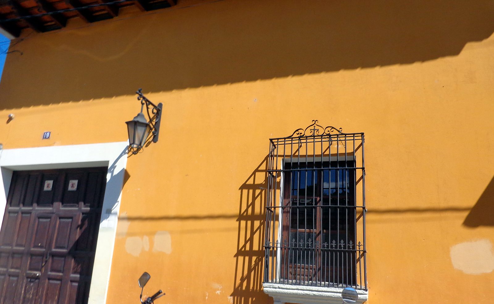 A yellow colonial house with an iron window in Antigua Guatemala
