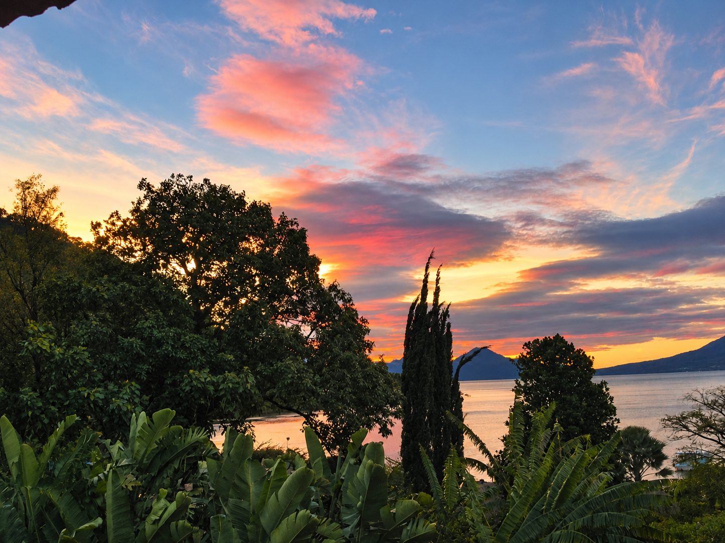 Sunset over Lake Atitlán with trees in front