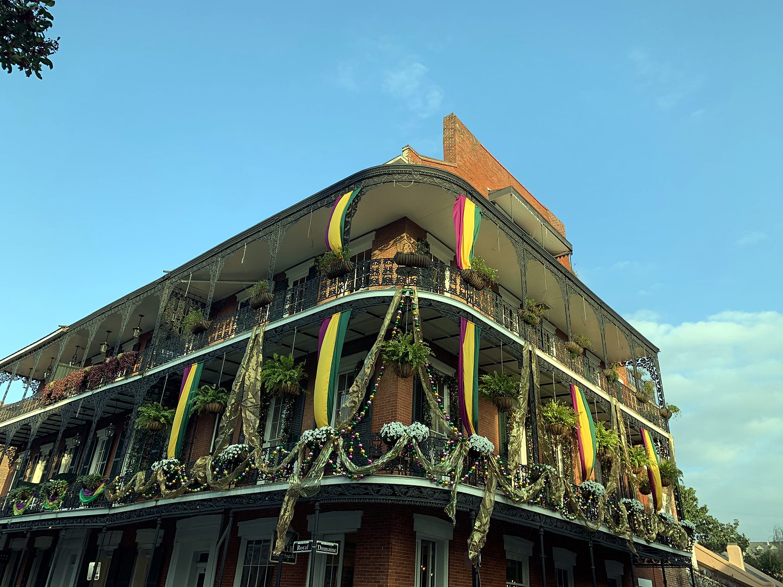 A corner building with balconies dressed for Mardi Gras
